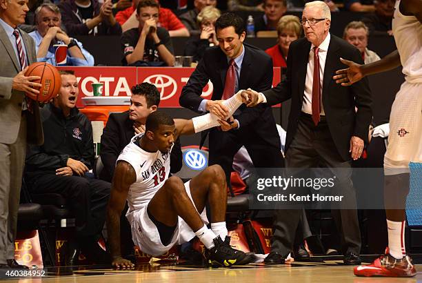 Winston Shepard of the San Diego State Aztecs is helped to his feet by head coach Steve Fisher after after falling into the bench area chasing...