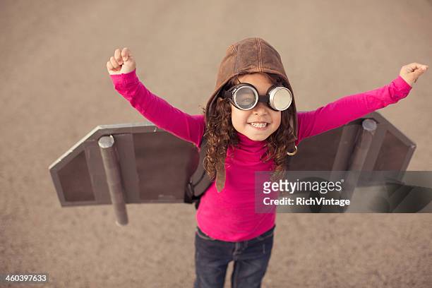 jeune femme en vêtements de pilote avec jouet avion ailes - flying goggles stock photos et images de collection