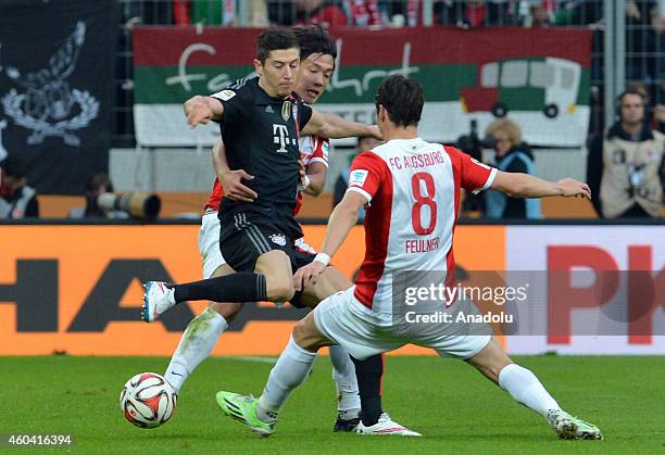 Robert Lewandowski of Bayern Munich in action against Jeong-Ho Hong and Markus Feulner of FC Augsburg during the Bundesliga soccer match between FC...