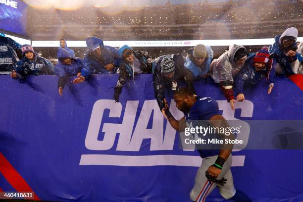 Justin Tuck of the New York Giants high-fives the crowd after defeating the Washington Redskins at MetLife Stadium on December 29, 2013 in East...