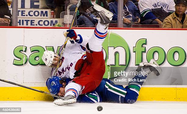Marc Staal of the New York Rangers falls on Derek Dorsett of the Vancouver Canucks after the two collided along the side boards during the third...