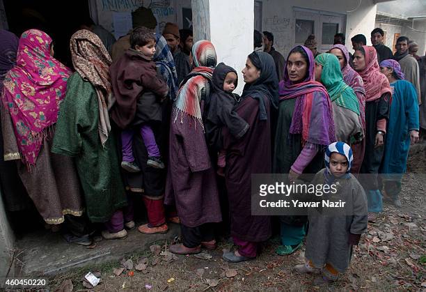 Kashmiri women voters holding their children as they wait in queue to cast their votes outside the polling station, during the fourth phase of...