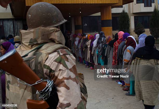 An Indian paramilitary soldier stands guard as Kashmiri voters wait in queue to cast their votes outside the polling station, during the fourth phase...