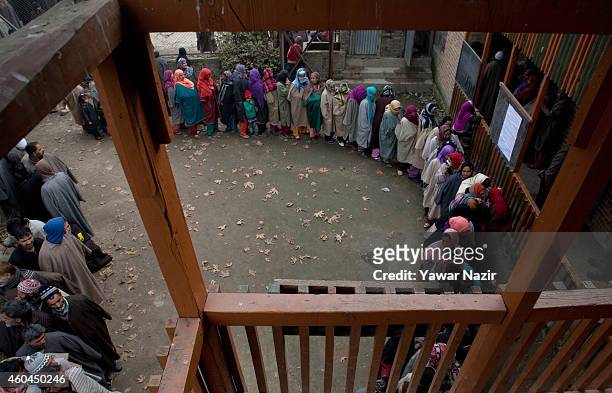 Kashmiri voters wait in queue to cast their votes outside the polling station, during the fourth phase of assembly elections on December 14, 2014 in...