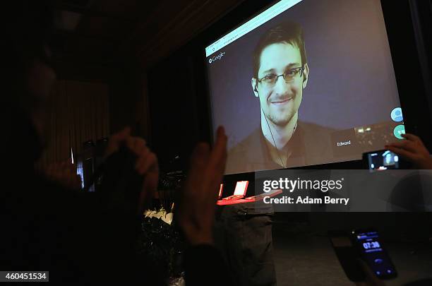 Audience members applaud as former National Security Agency contractor turned whistleblower Edward Snowden is seen on a video conference screen...