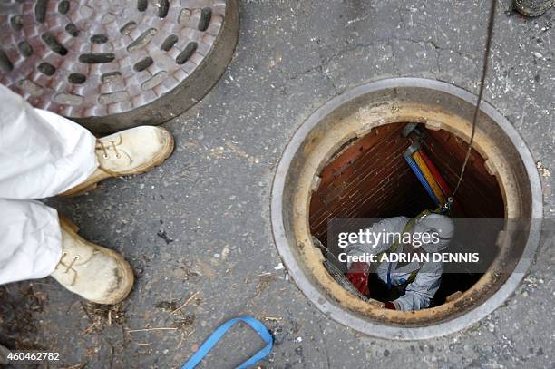 Thames Water sewer supervisor Vince Minney, emerges from a manhole in Whitehall after working in the Regent sewer in London on December 11, 2014....