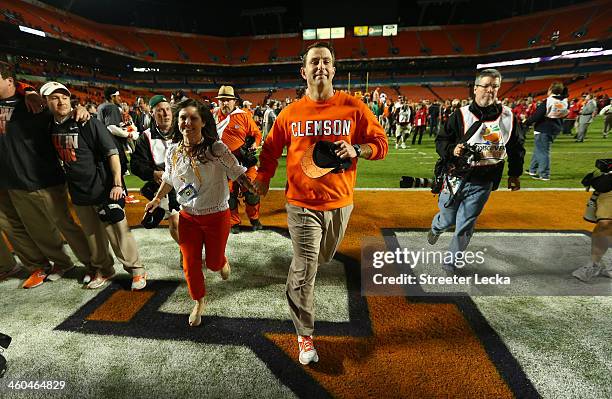 Head coach Dabo Swinney of the Clemson Tigers runs off the field with Kathleen Swinney after defeating the Ohio State Buckeyes during the Discover...