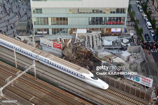 Bullet train runs in front of the aftermath as Tokyo Fire Department staff investigate near JR Yurakucho Station in Tokyo on January 4, 2014. A fire...