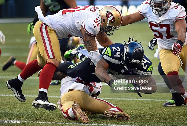 Running back Marshawn Lynch of the Seattle Seahawks dives forward with the ball as outside linebacker Dan Skuta of the San Francisco 49ers and inside...