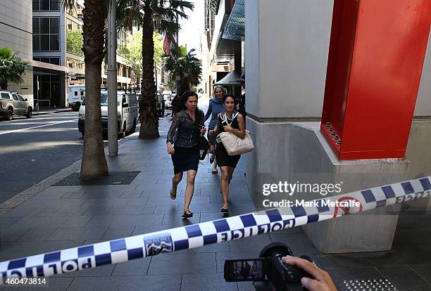 Ladies rush through Philip St past armed police at Lindt Cafe, Martin Place on December 15, 2014 in Sydney, Australia. Police attend a hostage...