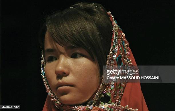 An Afghan child looks on as others from The Community Centre for the Disabled take part in a performance on child labour to honour "World Day Against...