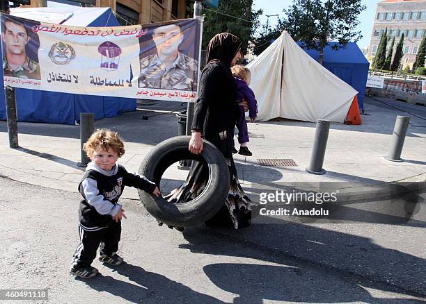 Labanese woman and her child walk through a street as she carries a tyre to burn in front of the government palace in Beirut, Lebanon during a...