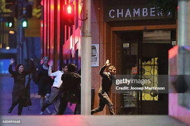 People run with their hands up from the Lindt Cafe, Martin Place during a hostage standoff on December 16, 2014 in Sydney, Australia. Police stormed...