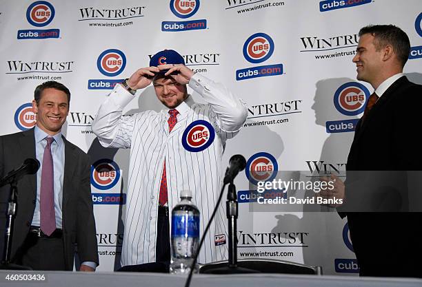 Pitcher Jon Lester puts on a Cubs hat during an introduction press conference as Chicago Cubs President Theo Epstein and general manager Jed Hoyer...