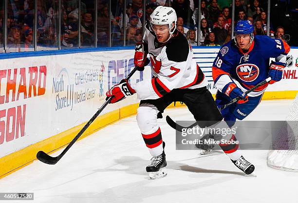 Jon Merrill of the New Jersey Devils is pursued by Ryan Strome of the New York Islanders at Nassau Veterans Memorial Coliseum on December 15, 2014 in...