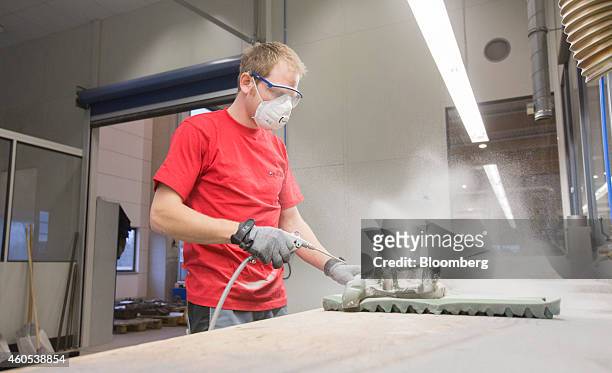 An employee uses a compressed air gun to clean a sand mold from a water jacket core automotive part at the Voxeljet AG 3-D printing plant in...