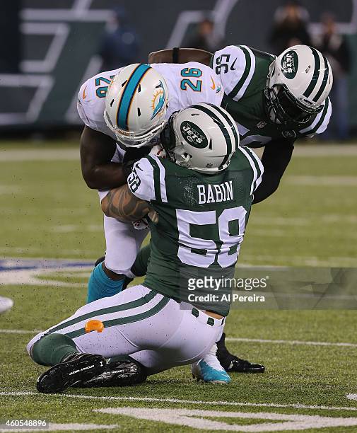 Linebacker Demario Davis and Linebacker Jason Babin of the New York Jets make a stop against the Miami Dolphins at MetLife Stadium on December 1,...