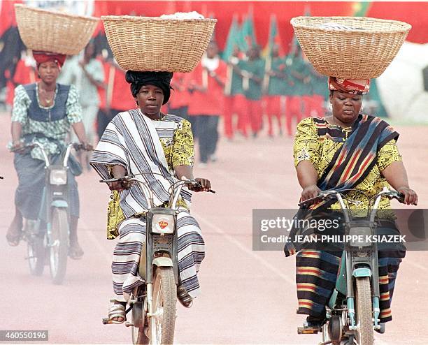 Women from Burkina Faso pass on mobylettes 07 February in Ouagadougou during the opening ceremonies for the African Nations Cup. The mobylette is one...