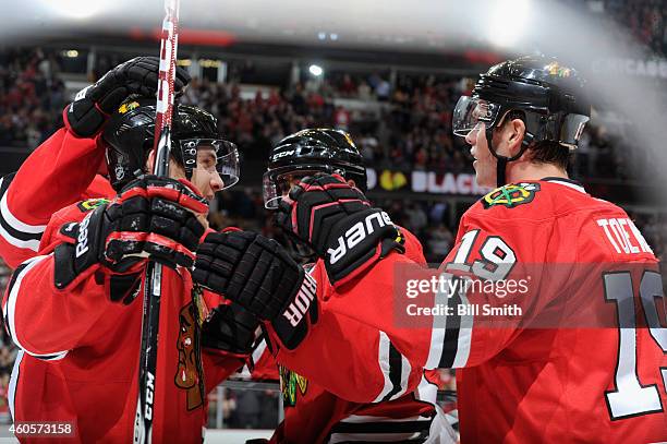 Jonathan Toews of the Chicago Blackhawks celebrates with Ben Smith and Johnny Oduya after scoring the third goal against the Minnesota Wild during...