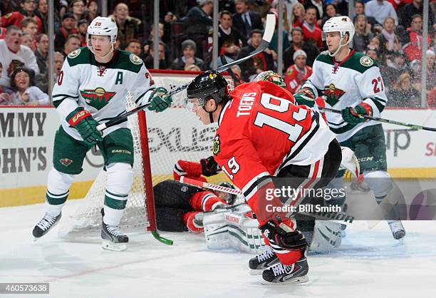 Jonathan Toews of the Chicago Blackhawks skates by Kris Versteeg, who was pushed into the goal, as Ryan Suter and Brett Sutter of the Minnesota Wild...