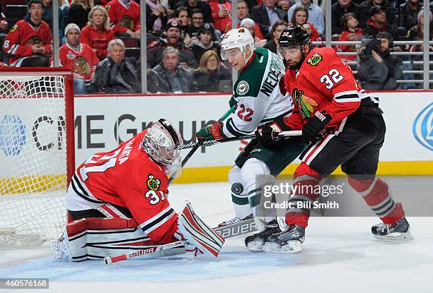 Nino Niederreiter of the Minnesota Wild and Michal Rozsival of the Chicago Blackhawks approach the puck as it flies toward goalie Antti Raanta during...