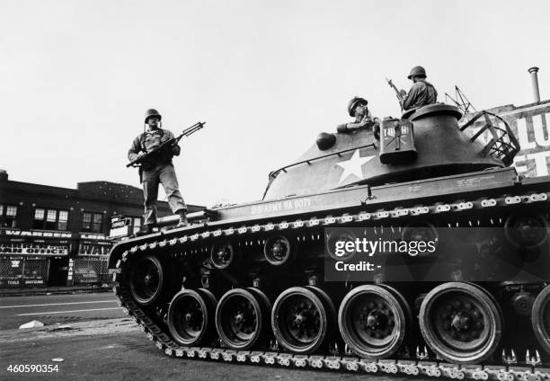 Federal soldiers stand guard on a tank in a Detroit street on July 25, 1967 during riots that erupted in Detroit following a police operation.