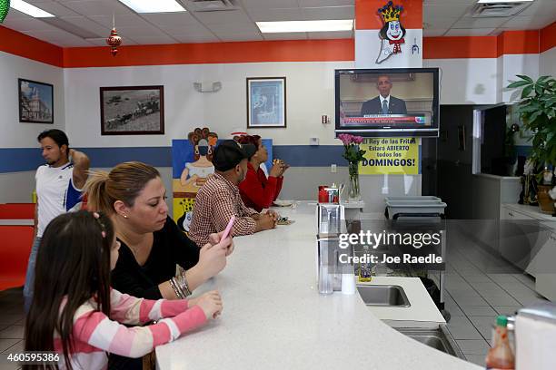 People sit at the lunch counter, at the El Rey de Las Fritas restaurant in the Little Havana neighborhood, as a television set shows U.S. President...