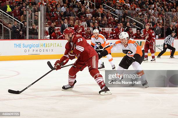 Derek Morris of the Phoenix Coyotes skates with the puck while being defended by Jay Rosehill of the Philadelphia Flyers at Jobing.com Arena on...