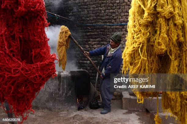 In this photograph taken on December 17, 2014 an Afghan worker dyes thread at a carpet manufacturer in Herat. Some 42,500 women and their families...