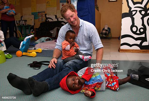 Prince Harry plays with two young children during a visit to the organisation supported by Sentebale 'Touching Tiny Lives' on December 8, 2014 in...