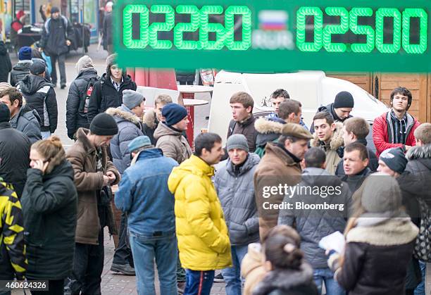 Pedestrians pass beneath an electronic board as it displays currency exchange rates in Kiev, Ukraine, on Wednesday, Dec. 17, 2014. Ukraine needs $15...