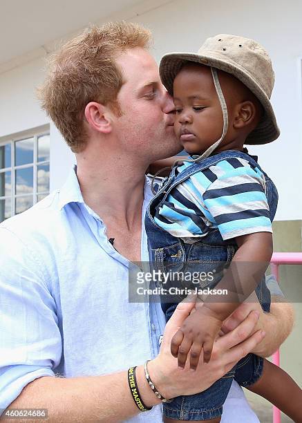 Prince Harry holds a young child during a visit to Thuso Centre for children living with multiple disabilities on December 7, 2014 in Bute-Bute,...