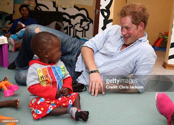 Prince Harry plays with two young children during a visit to the organisation supported by Sentebale 'Touching Tiny Lives' on December 8, 2014 in...
