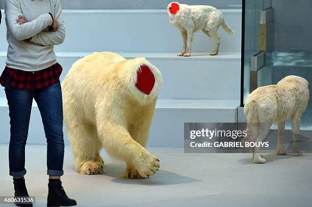Woman stands next to a decapitated bear, an art piece by Chinese artist Huang Yong Ping, during a press preview of the exhibition "Bugarach" at the...