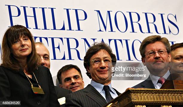Louis Camilleri, chairman and chief executive officer of Philip Morris International Inc., center, smiles as he and other company representatives...