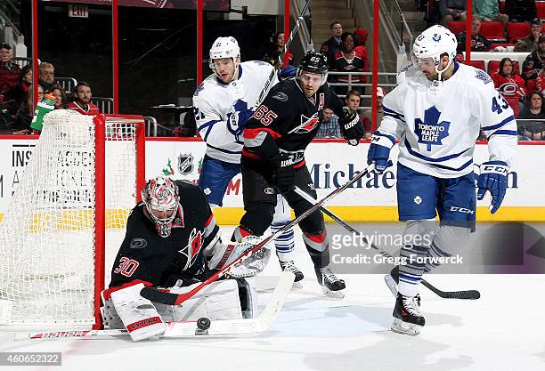 Nazem Kadri of the Toronto Maple Leafs tries to get his stick to a loose puck guarded by Cam Ward of the Carolina Hurricanes as James van Riemsdyk...