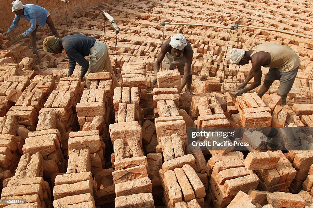 Laborers pile the  bricks in a factory on fogy and cold day...