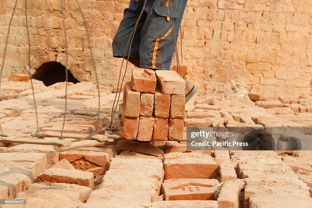 Laborer piles the  bricks in a factory on fogy and cold day...