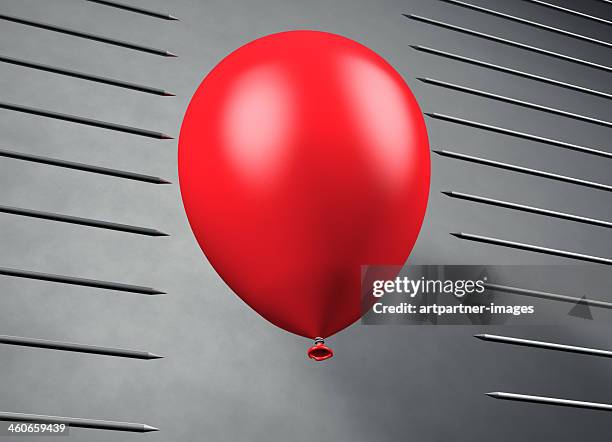 red balloon floats between pointed steel nails - metallic balloons stock pictures, royalty-free photos & images