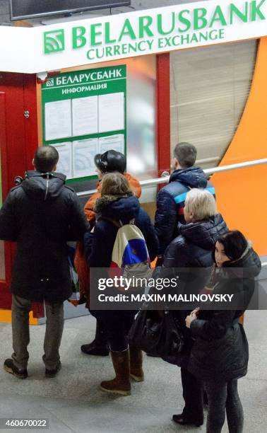 People stand in line at an exchange office in Minsk on December 19, 2014. People started converting rubles into dollars regardless of the National...