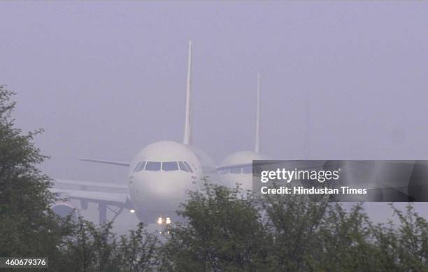 Passenger planes wait at the Runway of Indira Gandhi International Airport to take off in a dense foggy morning on December 18, 2014 in New Delhi,...