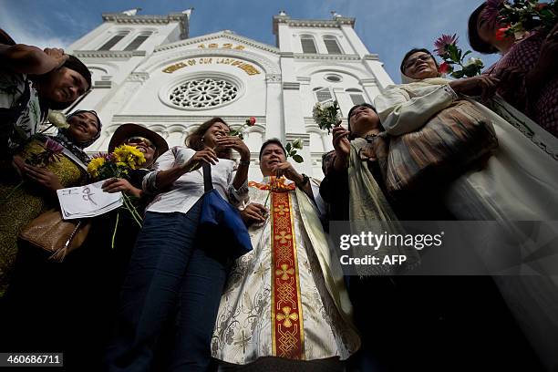 Malaysian activists pose for pictures as they hold flowers with a Catholic priest, Michael Chua in front of the Church of Our Lady of Lourdes during...