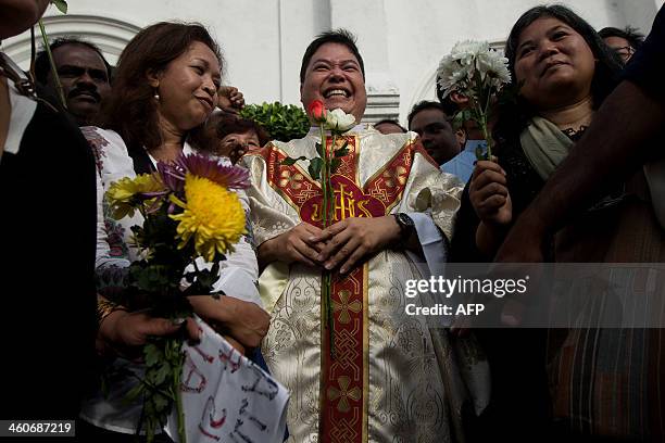 Catholic priest, Michael Chua holds roses as he poses for pictures with Malaysian activists in front of the Church of Our Lady of Lourdes during a...