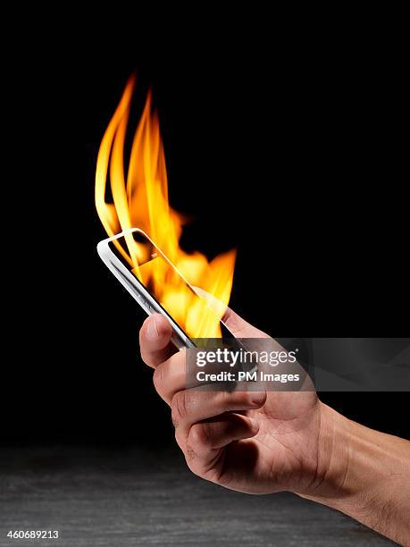 holding smartphone on fire - cell destruction stock pictures, royalty-free photos & images