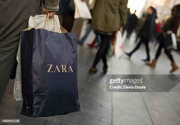 Shopper holds a a branded paper shopping bag from the Zara fashion store, operated by Inditex SA, on Gran via street on December 19, 2014 in Madrid,...