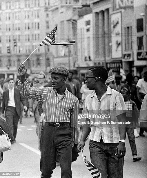 African-American teenage boys waving small American flags marching through Montgomery to Alabama State House with Selma to Montgomery marchers. On...