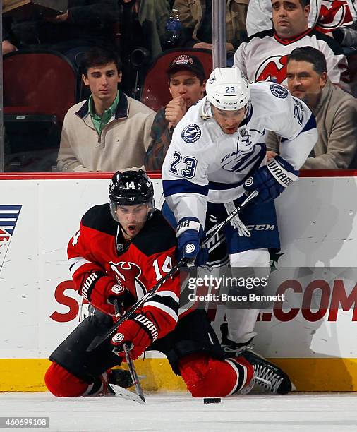 Adam Henrique of the New Jersey Devils attempts to control the puck while battling with J.T. Brown of the Tampa Bay Lightning at the Prudential...