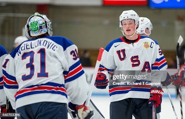 Jack Eichel of the USA National Junior Team talks to teammate Alex Nedeljkovic during NCAA exhibition hockey against the Boston University Terriers...