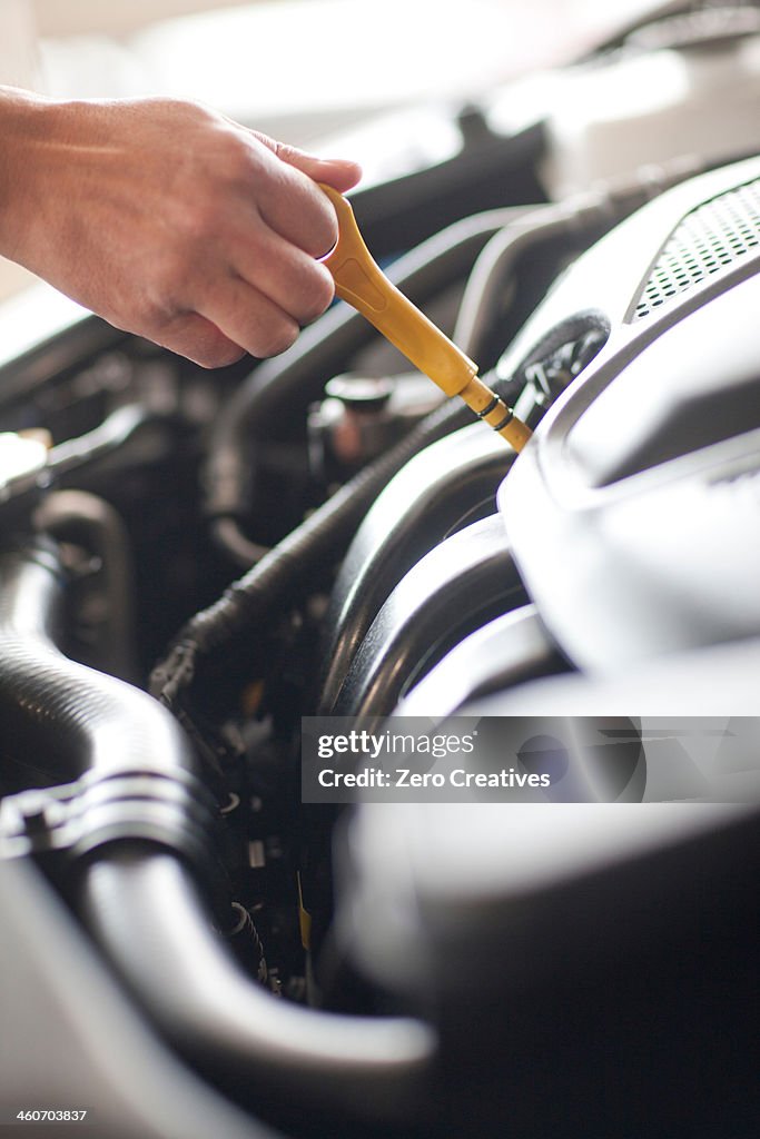 Mechanic checking oil dipstick on car engine