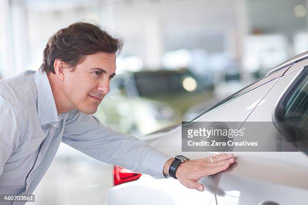 mid adult man examining car in showroom - customer appreciation stock pictures, royalty-free photos & images